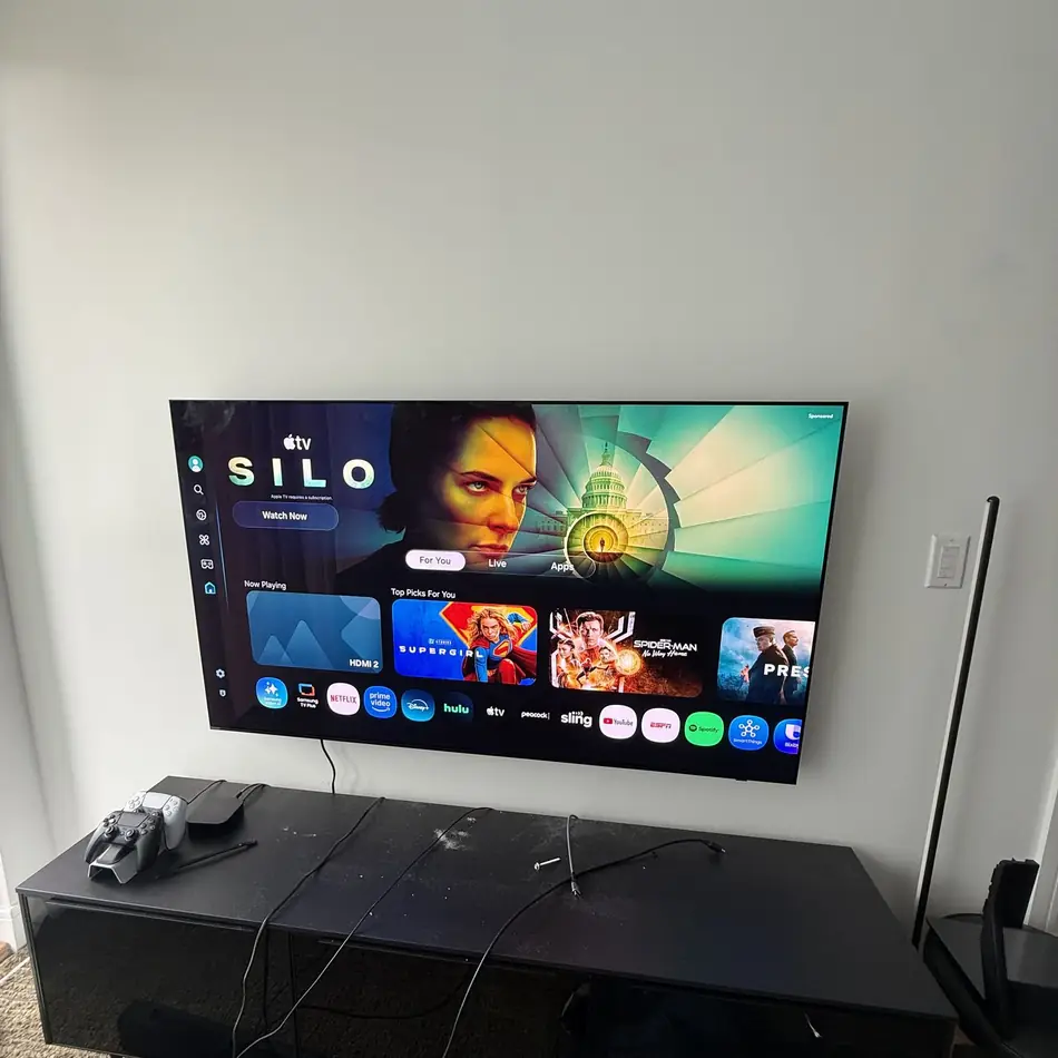 Wall mounted TV above a gaming console with cables dressed