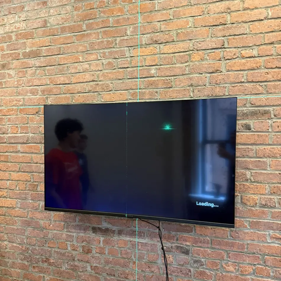 TV mounted on an exposed brick wall in NYC with a green laser level